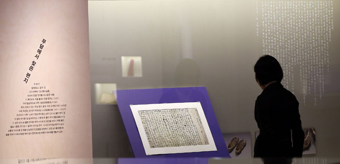 A museum-goer examines a letter written by a woman named 'Woni’s mom' during a press event for the exhibition on April 20. In the letter, written in 1586, a wife tells how much she cares for and misses her husband, who has passed away some time before. The letter was found in the tomb of Yi Eung-tae.