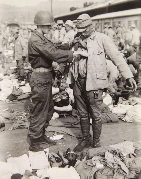  A Japanese soldier is searched before boarding a ship to return to Japan. 