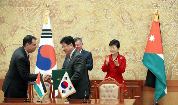 Minister of Trade, Industry and Energy Yoon Sang-jick (front row, right) shakes hands with his Jordanian counterpart during a signing ceremony for a memorandum of understanding that covers energy sector development and the renewable energy sector, on Sept. 11. President Park Geun-hye and King Abdullah II of Jordan oversee the signing ceremony.