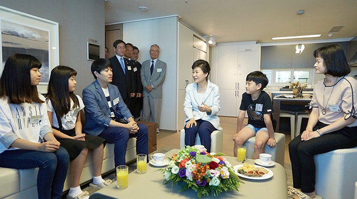 President Park Geun-hye (third from right) talks with members of a family who will move into the New Stay housing unit.