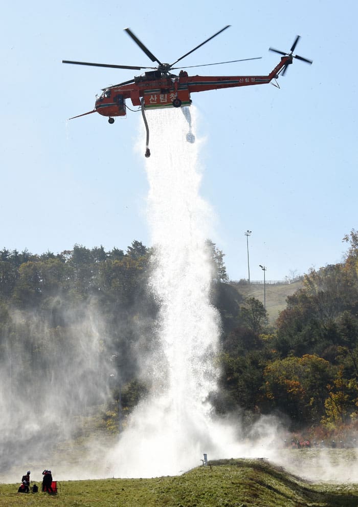 A helicopter drops water onto the fire's point of ignition.