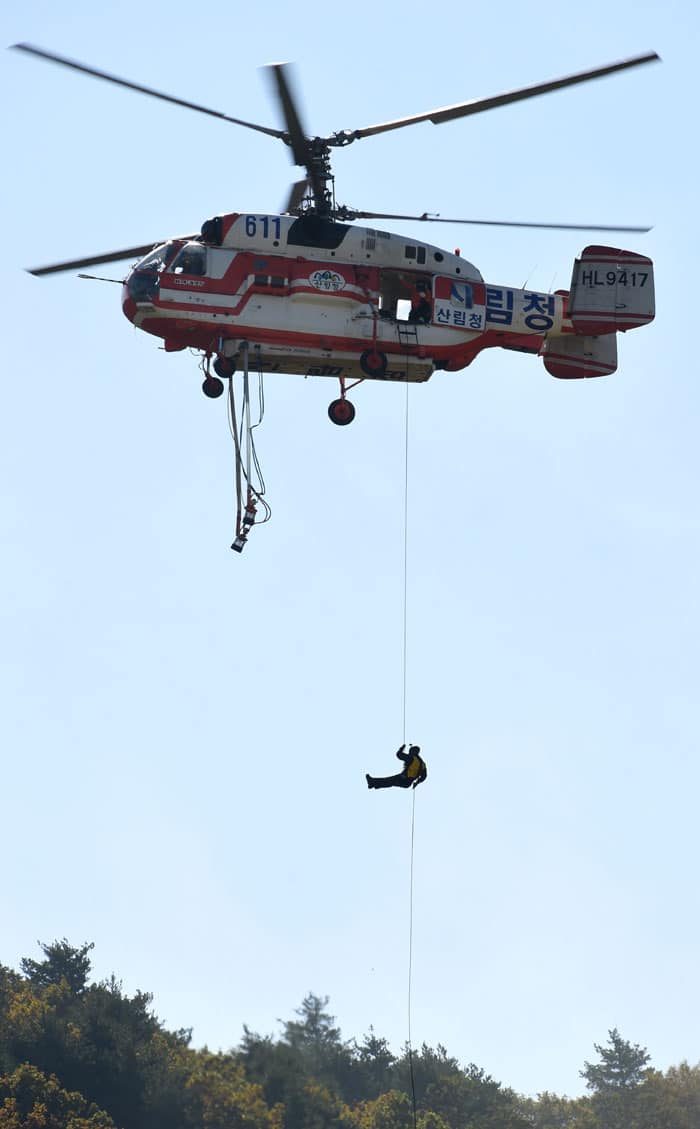 A fire fighter repels from a helicopter during a fire fighting demonstration.