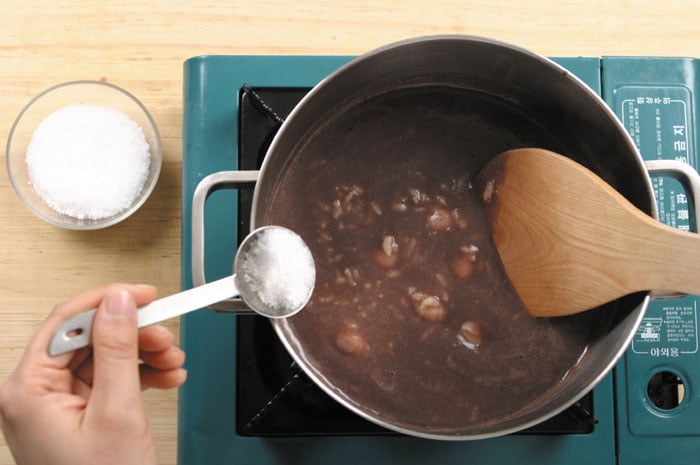 When the rice is cooked and has become soft, add the red bean mash and season with salt. You can put in small pieces of glutinous rice cake instead of rice balls, if you so desire.