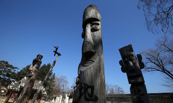 <i>Jangseung</i> and <i>sotdae</i> totem poles welcome visitors to the National Folk Museum of Korea.