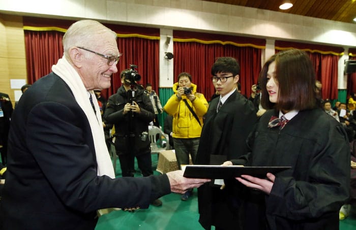 Chairman Brent Jett of the 40th Division Korean War Veterans association presents a graduation certificate to a student during the graduation ceremony.