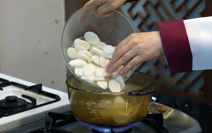 Add some soy sauce to make the soup a bit tastier. Boil it for a few minutes and add the sliced white rice cake to the boiling water. Add some salt to adjust to taste. To make the broth, you can also use simmered ox knee bone broth, brisket or shank.