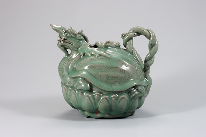 A turtle-dragon celadon pitcher from the 12th century is on display at the 'Earth, Fire, Soul -- Masterpieces of Korean Ceramics' exhibition. The pitcher shows the high artistry of Goryeo celadon ceramics. This work has a turtle with the head of a dragon sitting on a lotus flower.