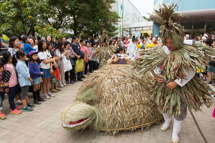 Visitors to the National Folk Museum of Korea enjoy a rendition of the turtle play taking place in the museum’s front plaza. The turtle play is a folk dance that was performed by young people who visit every house in a village in a wish for peace and good harvest across the village.