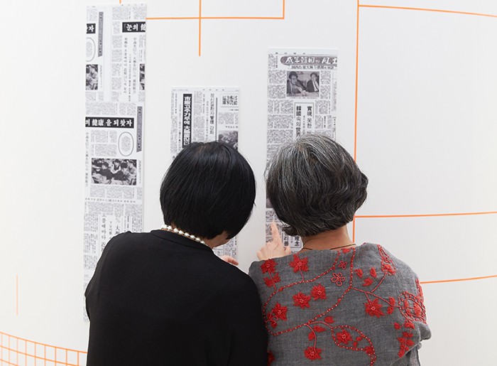 Visitors to the exhibition look at various newspaper print types on display.