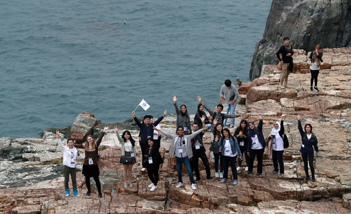 Korea.net honorary reporters wave from Taejongdae, above the blue sea, a historic site where Silla King Taejong Muyeol is said to have practiced his archery.