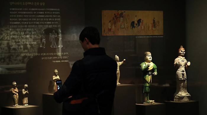 A museumgoer admires some of the pottery figurines on display in the Craftworks and Daily Life in Ancient China exhibition at the National Museum of Korea. Each of the items on display is introduced with related drawings, paintings, rubbed painting of stone inscriptions, or other visual materials to help visitors better understand the lifestyle of ancient East Asians.