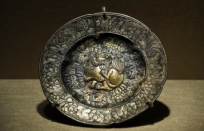 A gilded silver plate has a lion and flower design.