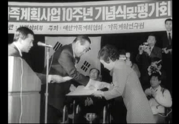 An award is given out during a ceremony to mark the 10th anniversary of a family planning program in 1971. The Family Planning Association of Korea actively carried out various birth control programs in those days. The above is a TV image from Daehan News.