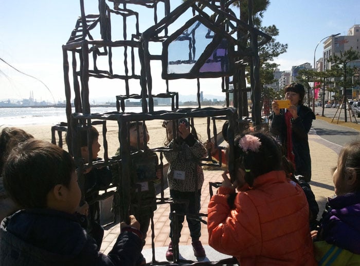 Students listen to an explanation about a steel work of installation art on display in Pohang.