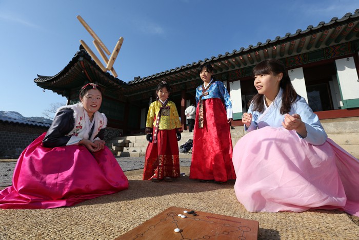 Visitors wearing Hanbok play the <i>yunnori</i> board game (윷놀이) at Gyeongbokgung Palace.