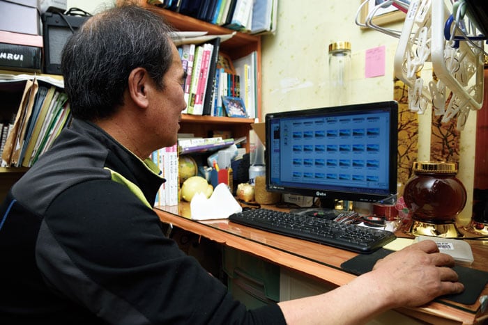 Wild herb collector Go Bong-jin sorts photos of wild herbs he has collected on his computer.