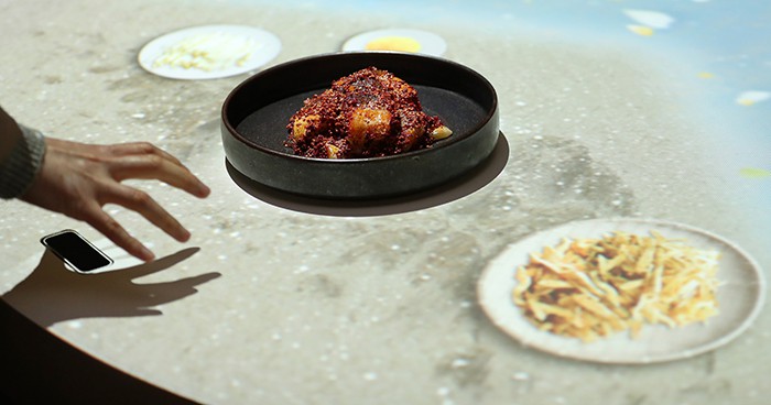 The recipe for <i>hwangtae sikhae</i> dried and fermented pollock (황태식해) is explained to a visitor at the media table.