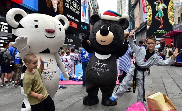 Children on June 23 pose for photos at a promotional booth in New York's Time Square with Soohorang the white tiger and Bandabi the Asiatic black bear, the two mascots of the PyeongChang 2018 Winter Olympics and Paralympics. (Korea Tourism Organization)