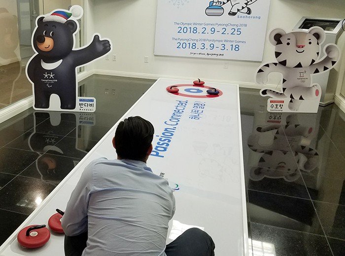 A visitor on June 24 tries the Winter Olympic sport of curling at a promotional booth within the Korean Cultural Center in Los Angeles. (Korean Cultural Center, LA)