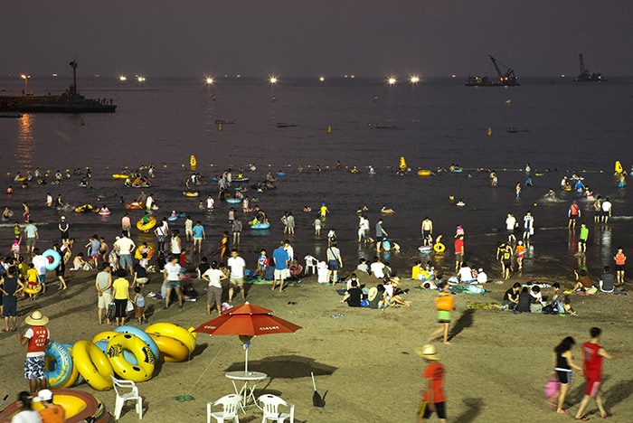 Jeju’s Hyeobjae, Hamdeok, Iho Tewoo and Samyang beaches now allow swimmers to stay two more hours after dark, until 9 p.m., for a limited time until Aug. 15. In the photo above, visitors enjoy Iho Tewoo Beach late at night. (Jeju Tourism Organization)