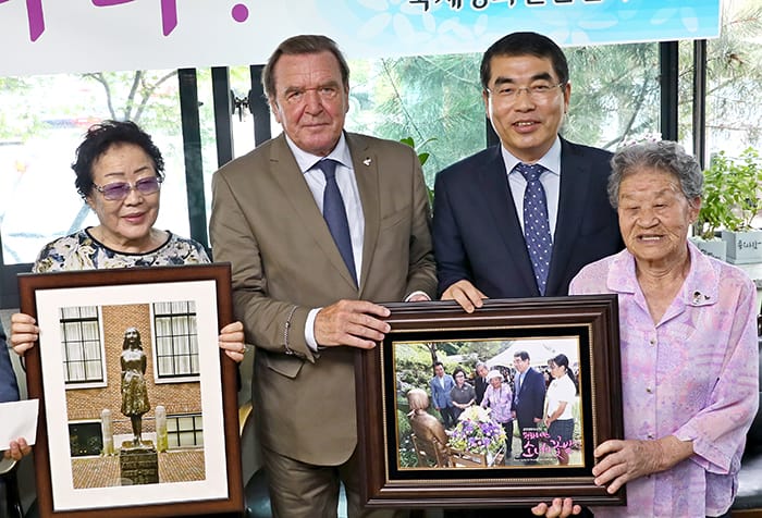 Former German Chancellor Gerhard Schröder visits survivors of sexual slavery in colonial times and World War II and delivers a photograph of a statue of Anne Frank, at the House of Sharing, a shelter for the victims, in Gwangju, Gyeonggi-do Province, on Sept. 11. Gwangmyeong Mayor Yang Ki-dae hands him a photograph of a flower garden that students at the Statue of Peace, a monument that symbolizes the survivors of sexual slavery.