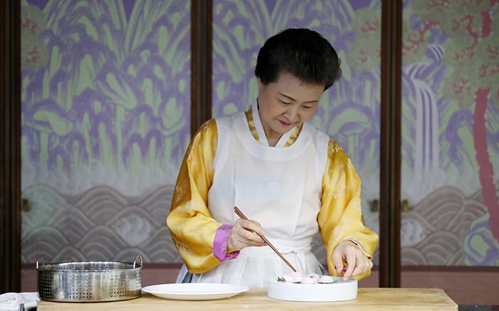 Director Yoon Sook-ja of the Institute of Traditional Korean Food takes the rice cake pieces out of the steamer and places them on the plate.
