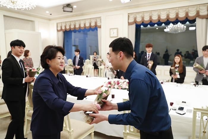 First lady Kim Jung-sook invites to Cheong Wa Dae on May 17 members of a support group that helps institutionalized youth become self-supporting. In the photo, first lady Kim offers roses to the guests during a dinner. (Cheong Wa Dae)