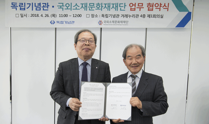 Lee Jun-Sik, president of the Independence Hall of Korea (left), and Ji Geon-gil, chairman of the Overseas Korean Cultural Heritage Foundation, hold up a written agreement at the Independence Hall of Korea in Cheonan City, Chungcheongnam-do Province, on April 26. (Independence Hall of Korea)