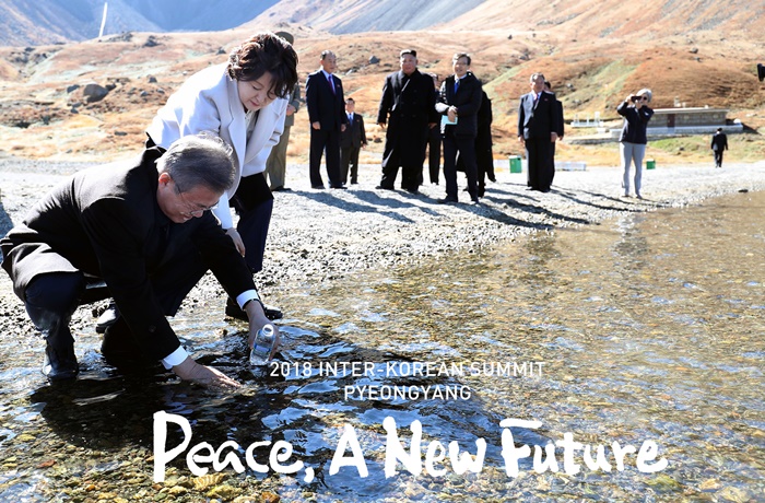 President Moon Jae-in (left) fills up a bottle with water from Cheonji Lake atop Baekdusan Mountain on Sept. 20. (Pyeongyang Press Corps)