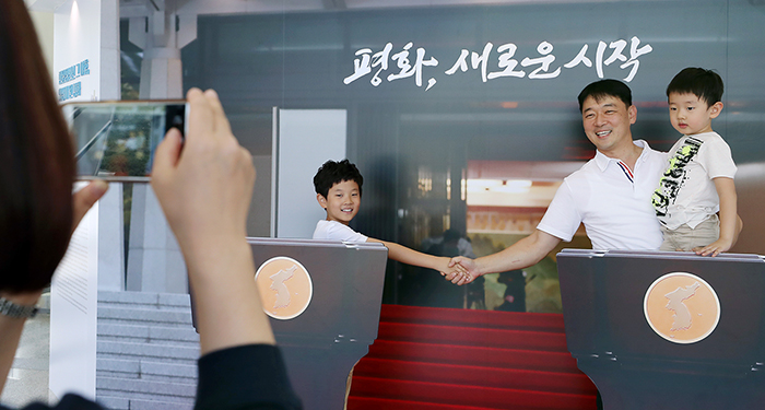 Visitors to a special exhibition about inter-Korean summits, titled 'Peace, a New Start,' pose for a commemorative photo at the official photo zone for the Panmunjeom Declaration at the Sarangchae exhibition space, at Cheong Wa Dae on Sept. 9. (Cheong Wa Dae)