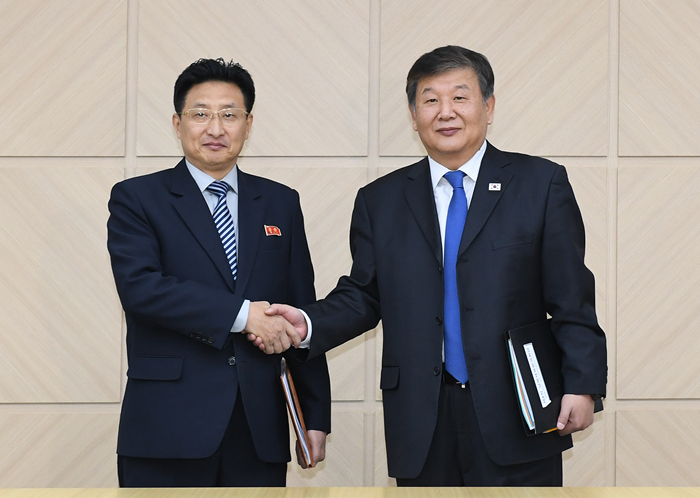 South Korean Deputy Culture, Sports and Tourism Minister Roh Tae-kang (right) and North Korean Vice Physical Culture and Sports Minister Won Kil-u on Dec. 14 shake hands at the inter-Korean joint liaison office in Gaeseong. (Ministry of Unification)