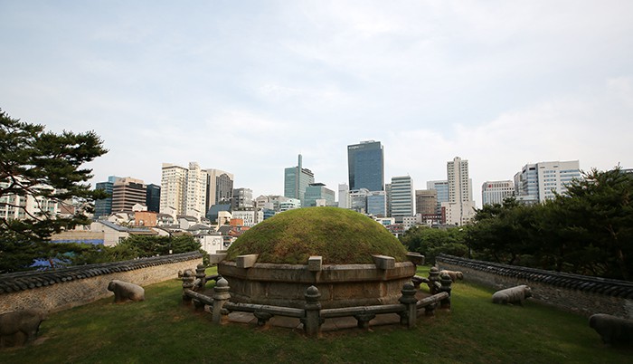 Jeongneung is the tomb of King Jungjong (r. 1506-1544), the 11th king of Joseon. The tomb is seen from the front and the skyline in the background shows a typical urban scene. 